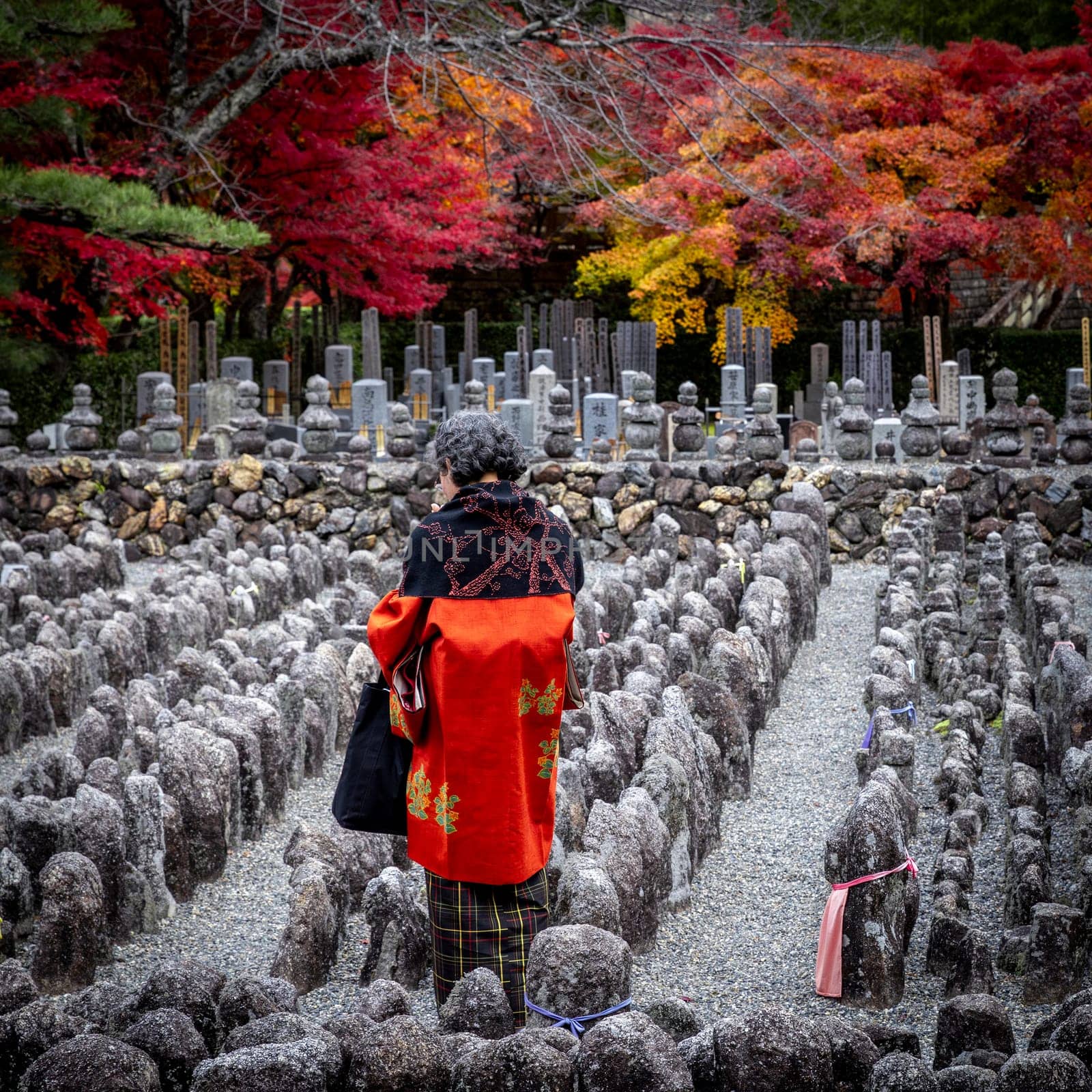 KYOTO/JAPAN - November 27, 2023:Elderly woman prays in the Adashino Nenbutsuji cemetery