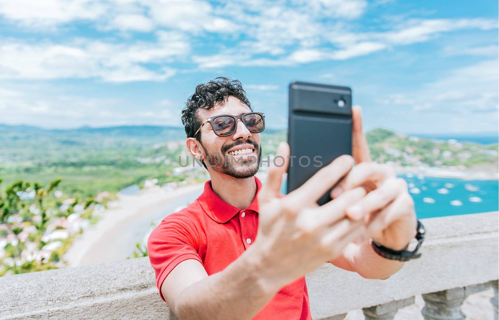 Happy tourist man taking a selfie at a beach viewpoint. Handsome man taking a selfie at the viewpoint of San Juan del Sur