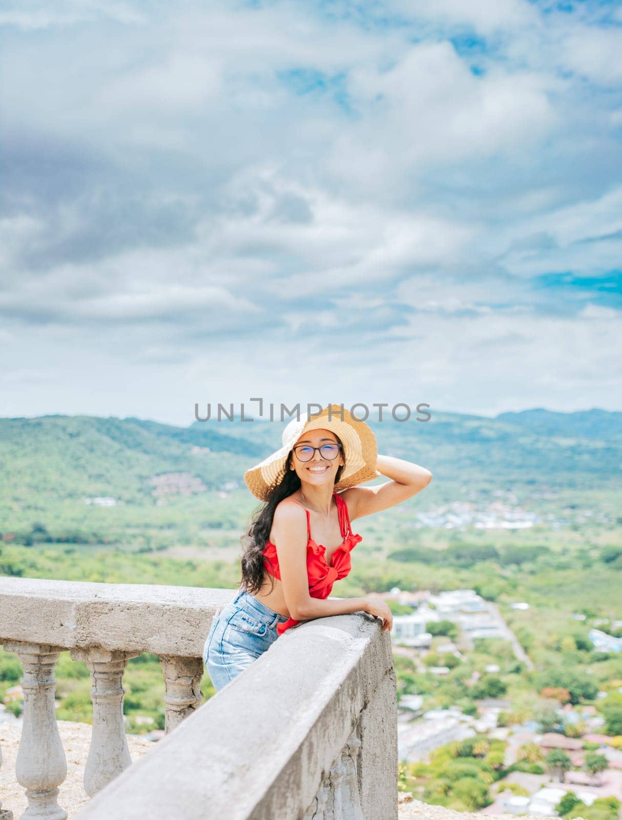 Happy tourist woman in hat on a viewpoint. Portrait of vacationer girl in a viewpoint. Travel and tourism promotion concept