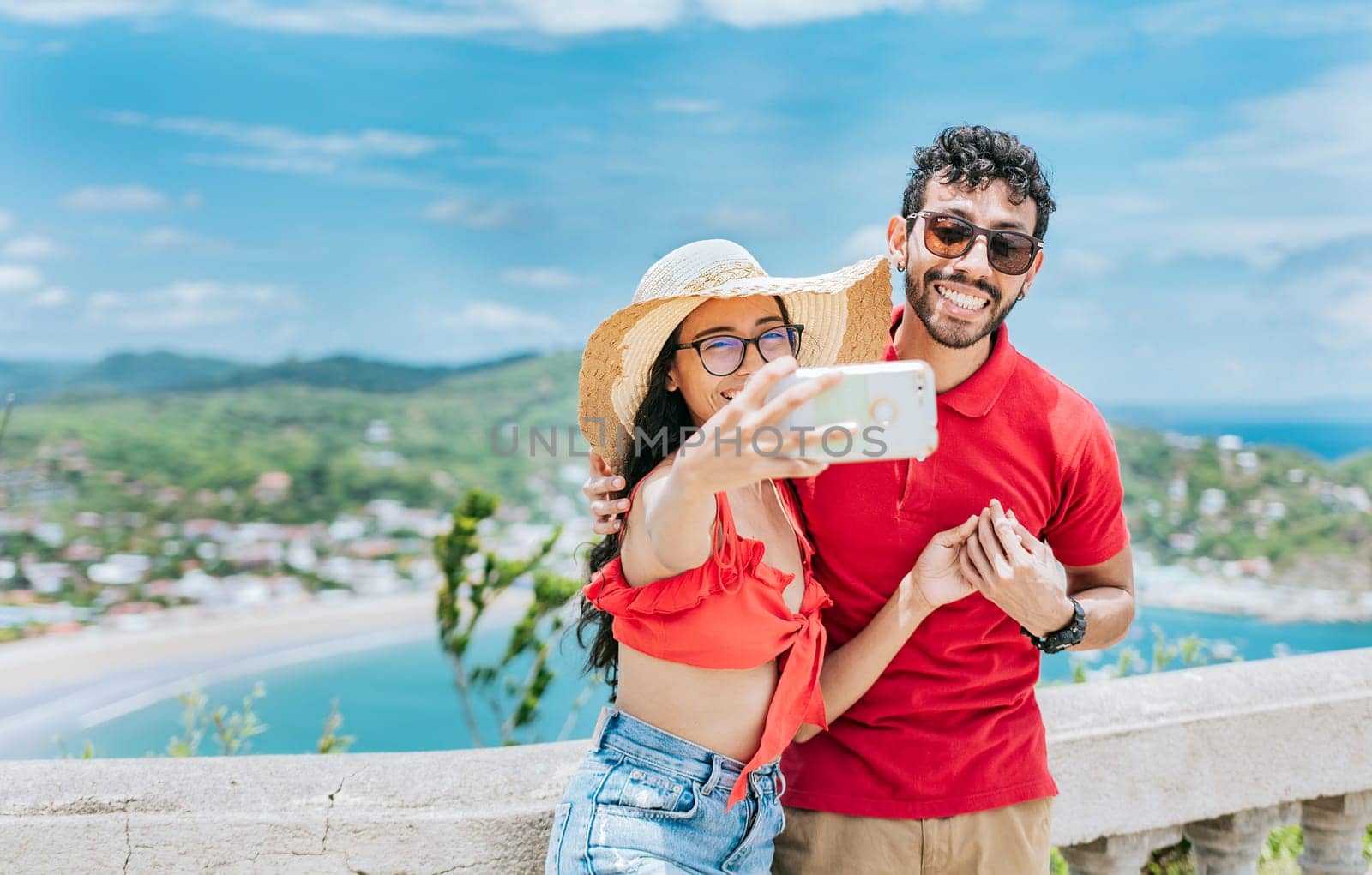 Happy Young tourist couple taking a selfie in a beautiful viewpoint. Smiling tourist couple taking a selfie at the viewpoint of San Juan del Sur.