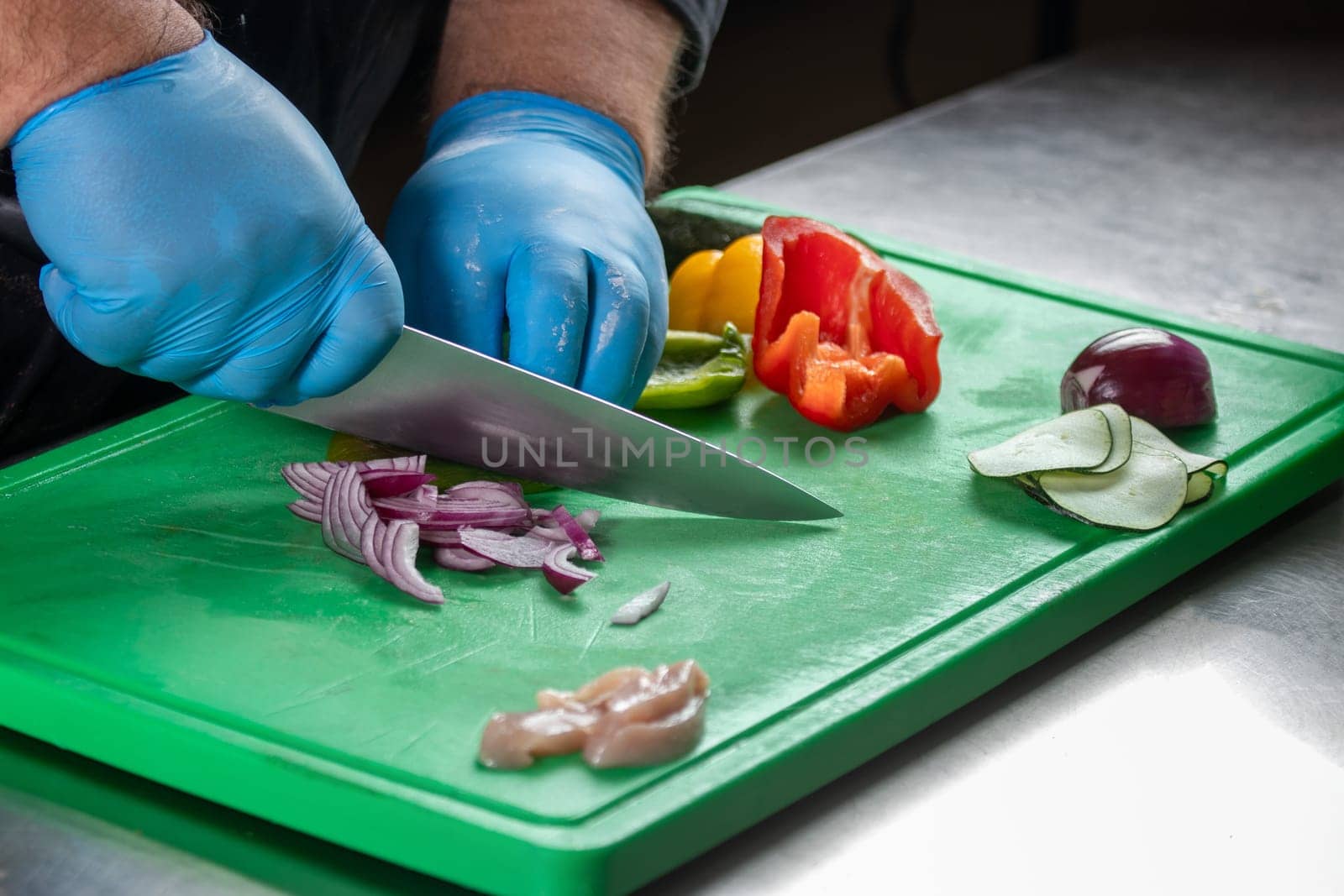 A skilled chef meticulously prepares fresh ingredients, including meat, onions, peppers, and cucumbers, for a flavorful recipe, showcasing culinary expertise and attention to detail.
