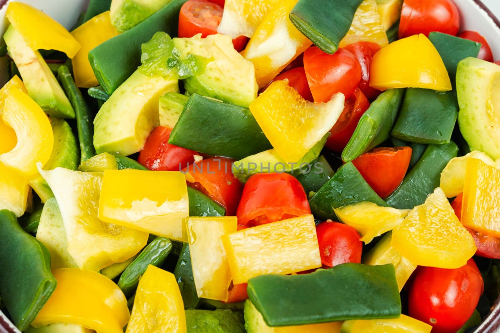 Vegetable salad with bell pepper, tomato, avocado and runner beans in bowl on rustic wooden table. Rustic style.