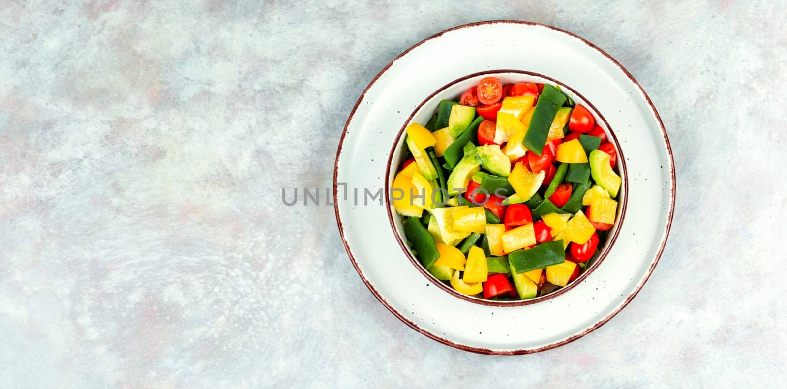 Vegetable salad with bell pepper, tomato, avocado and runner beans in bowl on rustic wooden table. Rustic style.