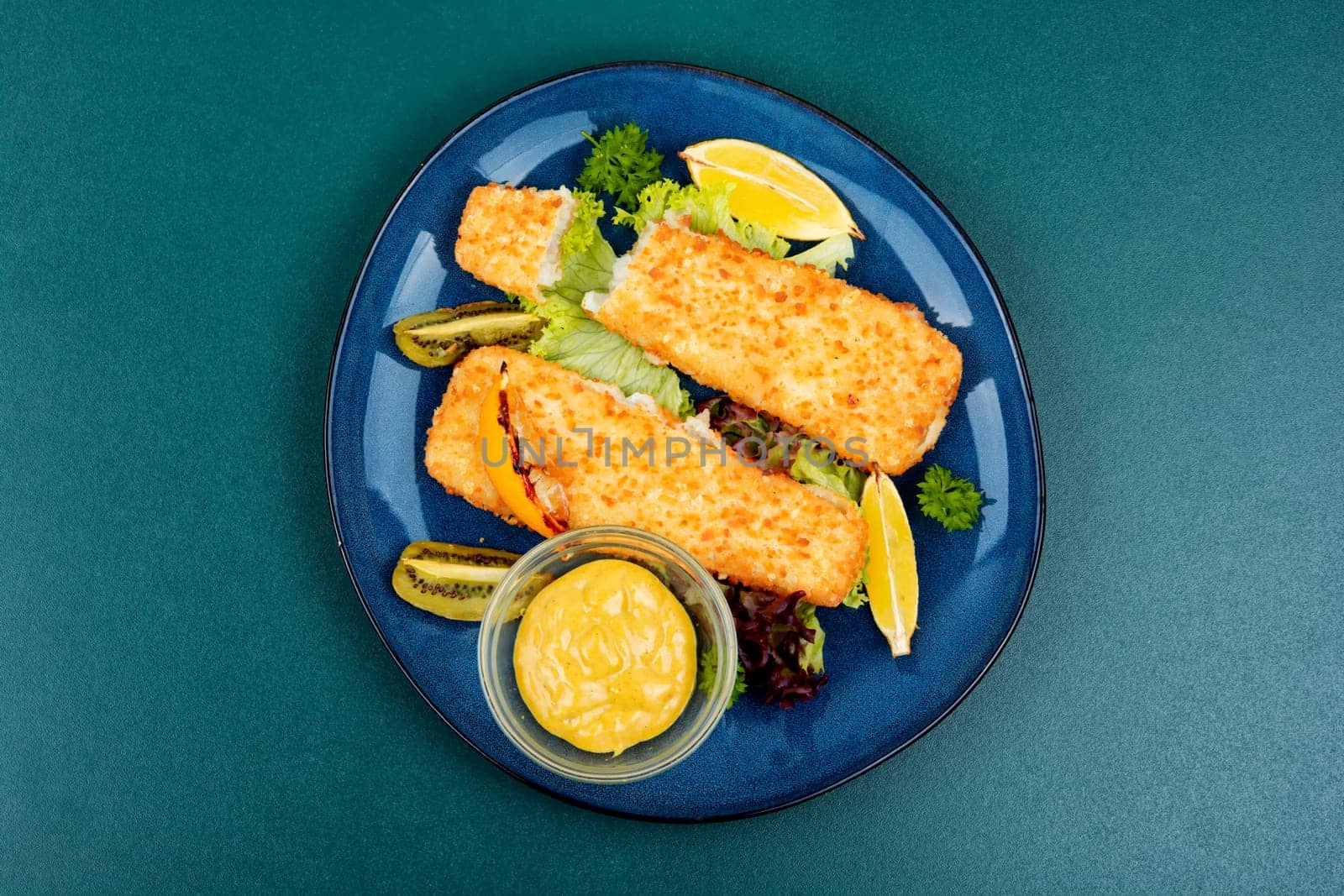 Pollock fillet roasted in bread crumbs served with sauce and kiwi. Fish in chips.