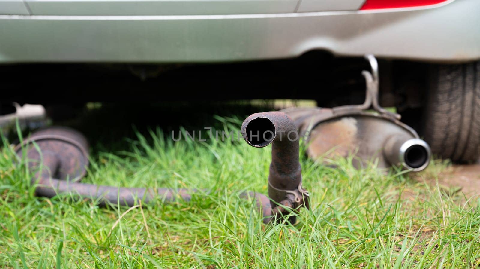 Broken exhaust and muffler of a car, rusted silencer fallen down on the road, breakdown of vehicle