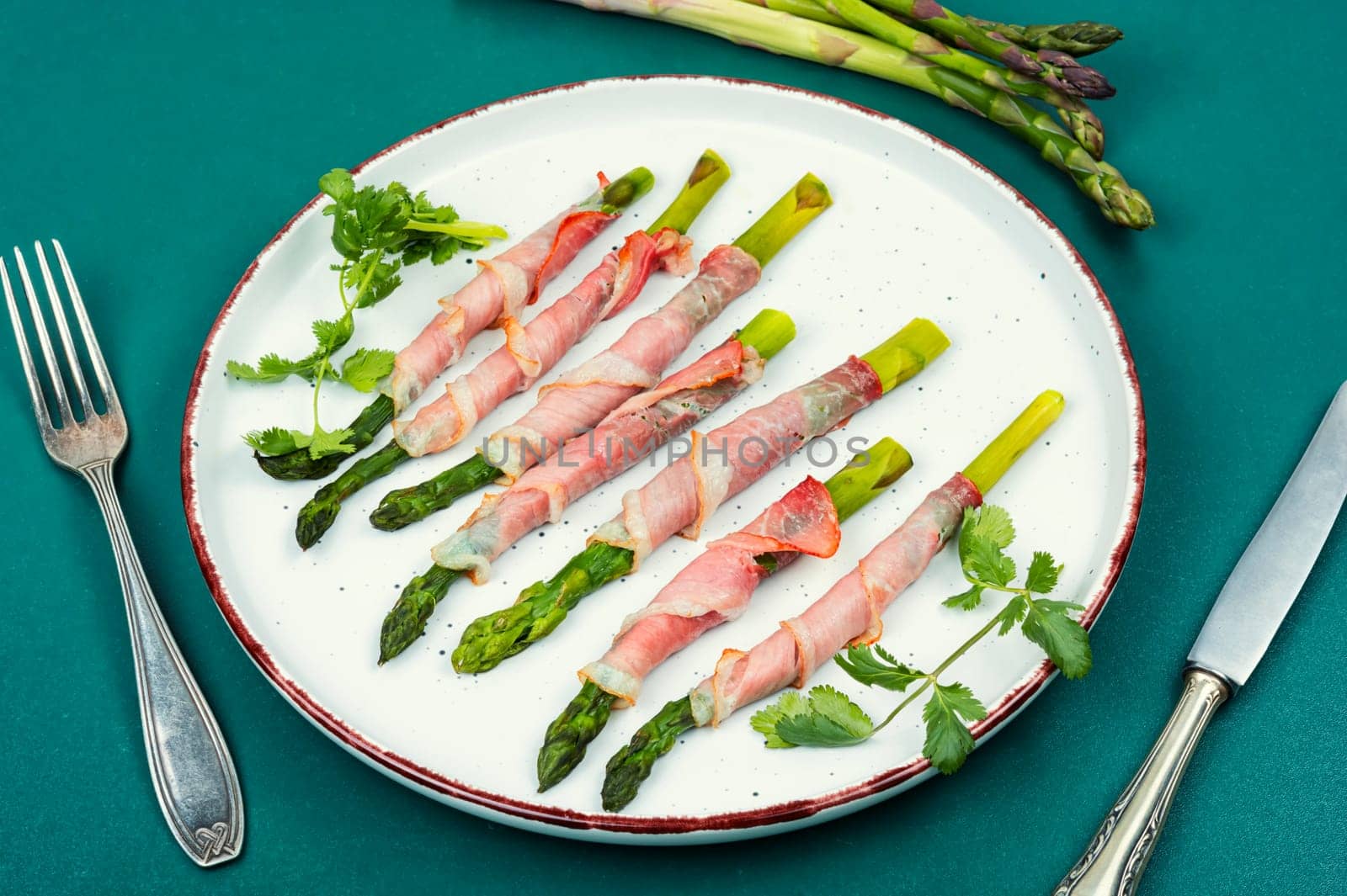 Green asparagus baked in bacon on a wooden background, rustic style. Space for text