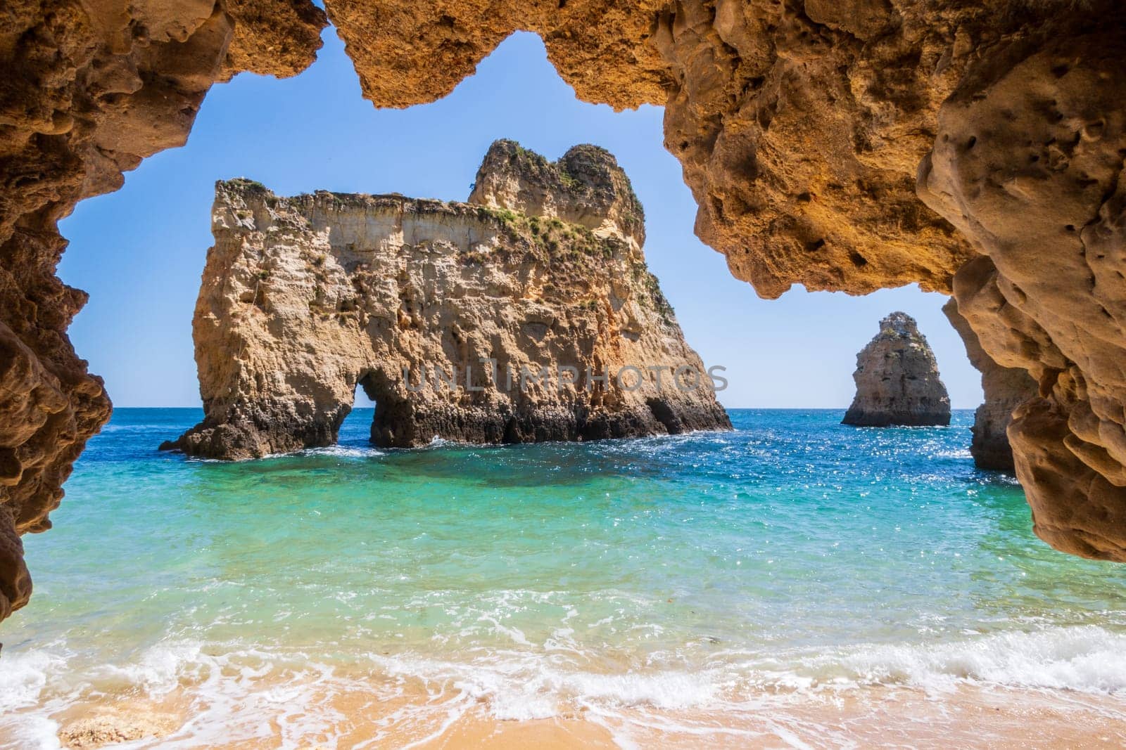 Small, heavenly and difficult to access beach photographed from inside a cave, near Portimão in the Algarve region of Portugal