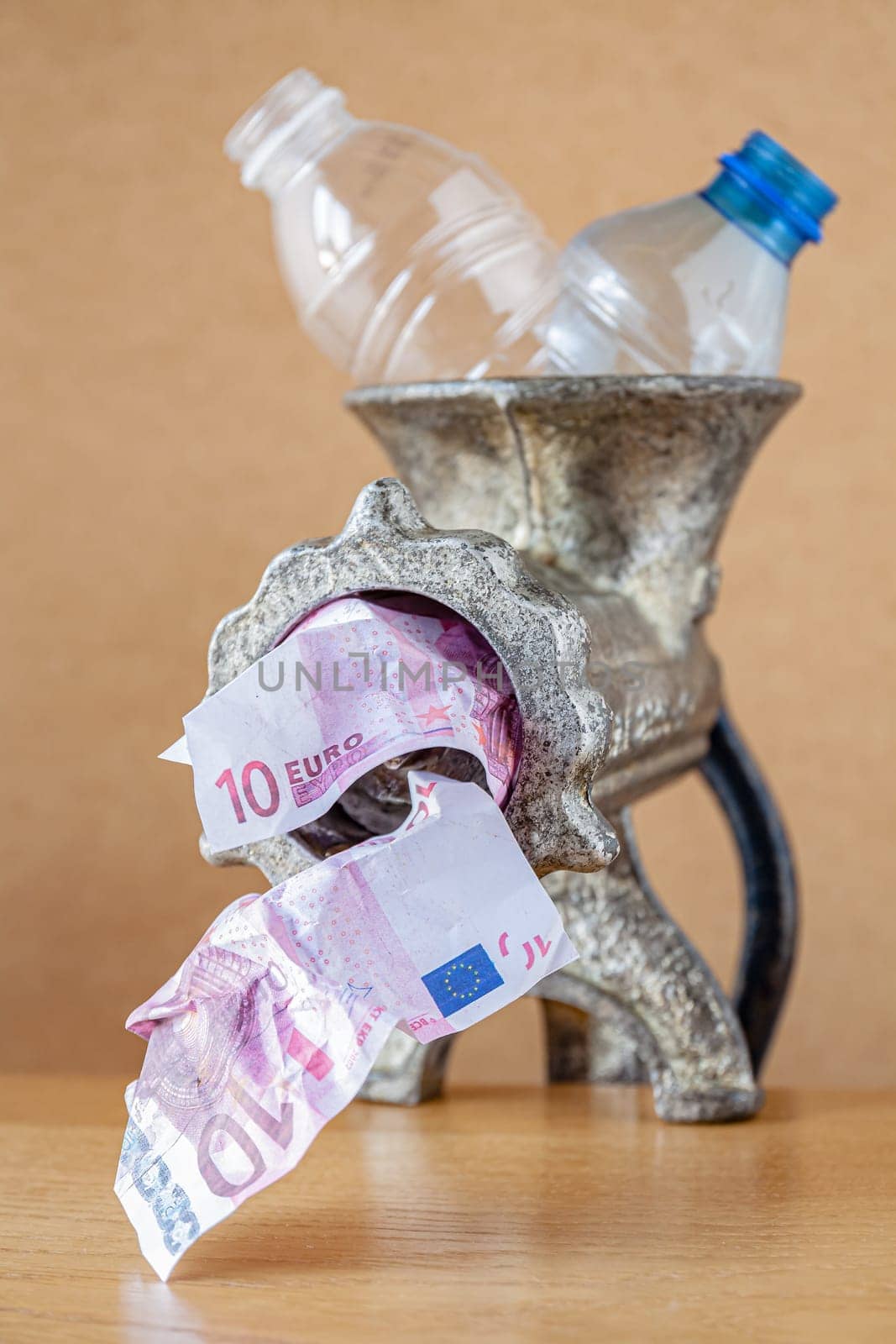 A meat grinder as a recycling machine turning plastic bottles into banknotes. Selective focus with shallow depth of field.