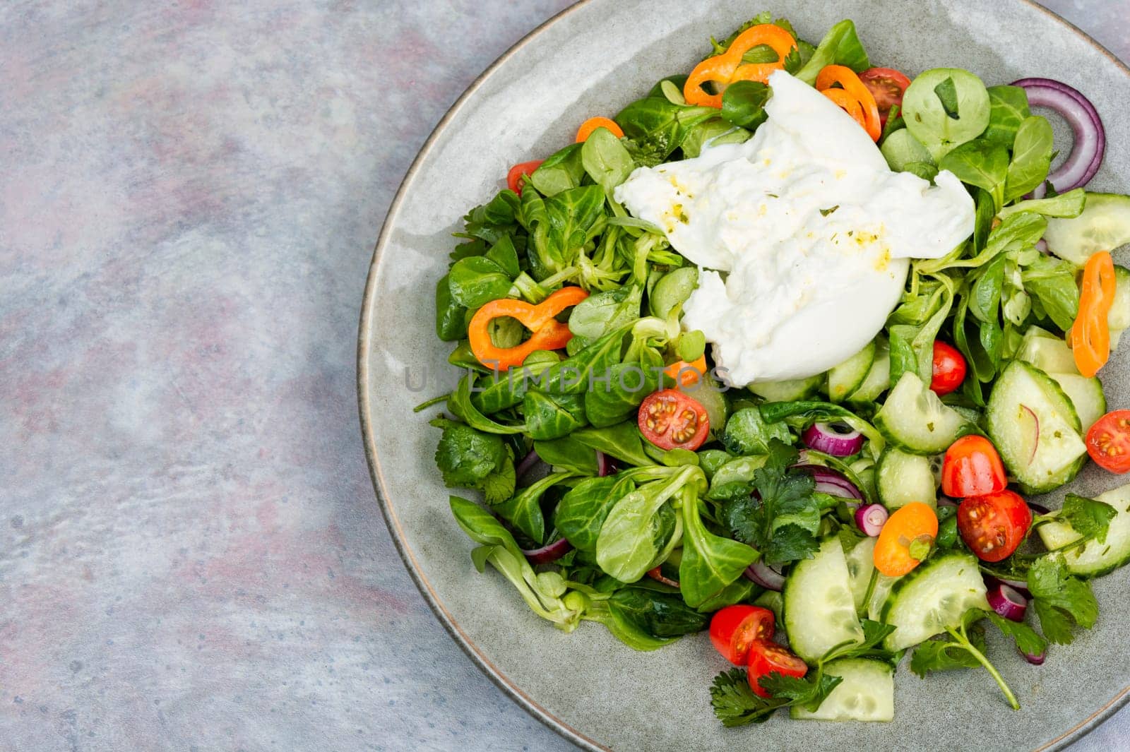 Salad of greens, tomatoes, cucumbers and fresh cream cheese Burrata. Burrata salad with vegetables on rustic wooden table