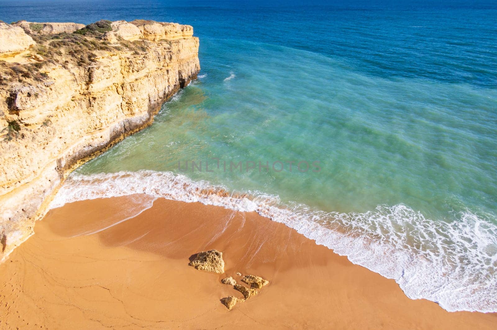 Top view over ocean and wavescrushing on sandy beach near Albufeira, Algarve, Portugal