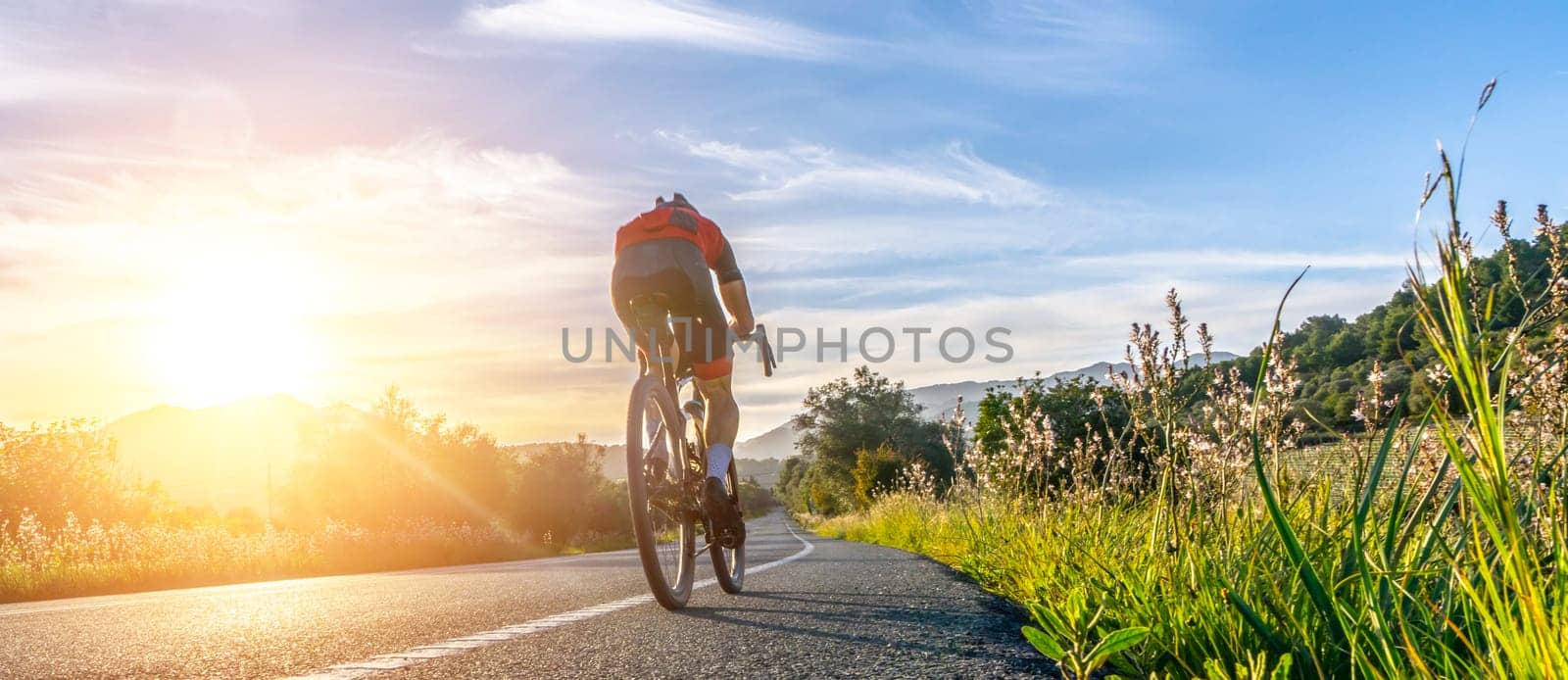 Mature Adult on a racing bike climbing the hill at mediterranean sea landscape coastal mountain road - mallorca mountains
