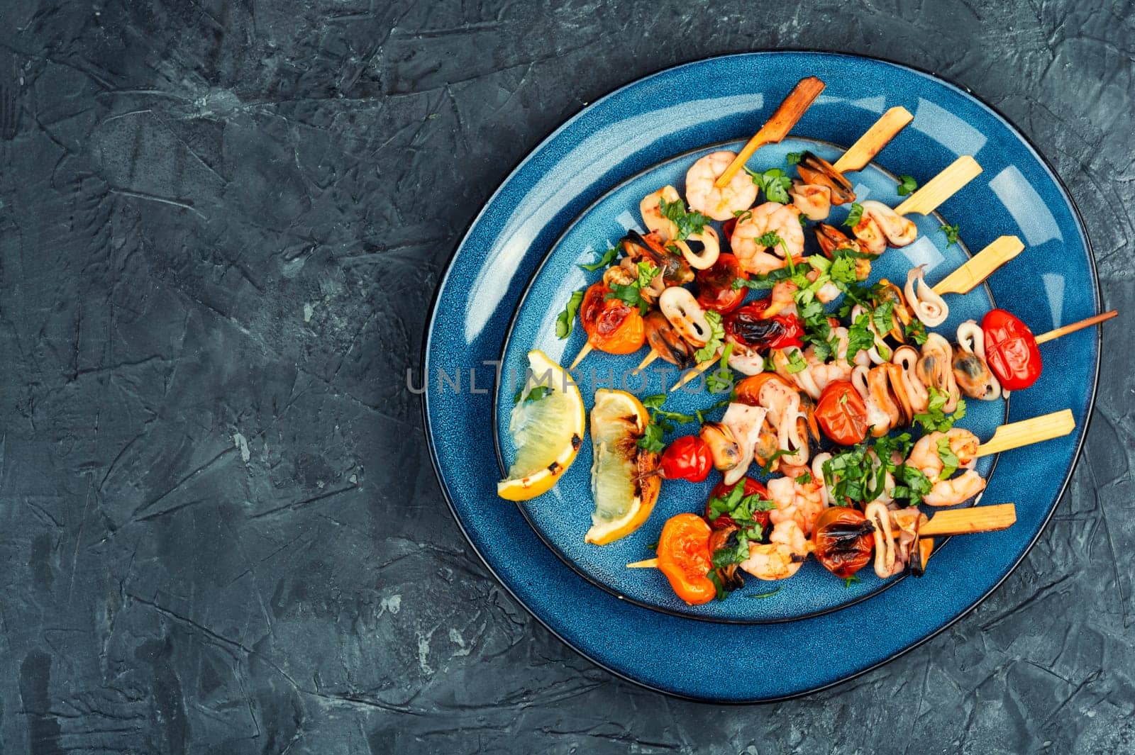Barbecue or grilled seafood kebabs, shrimps prawns, mussels and grilled squid on skewers. Space for text.