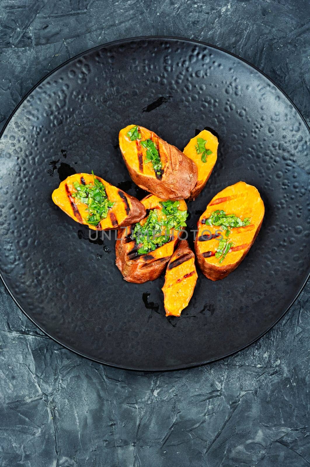 Homemade grilled sweet potato, batata with olive oil and herbs. Vegan cuisine.