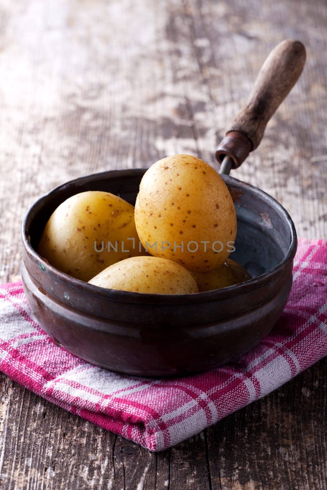 four cooked potatoes in an old pan