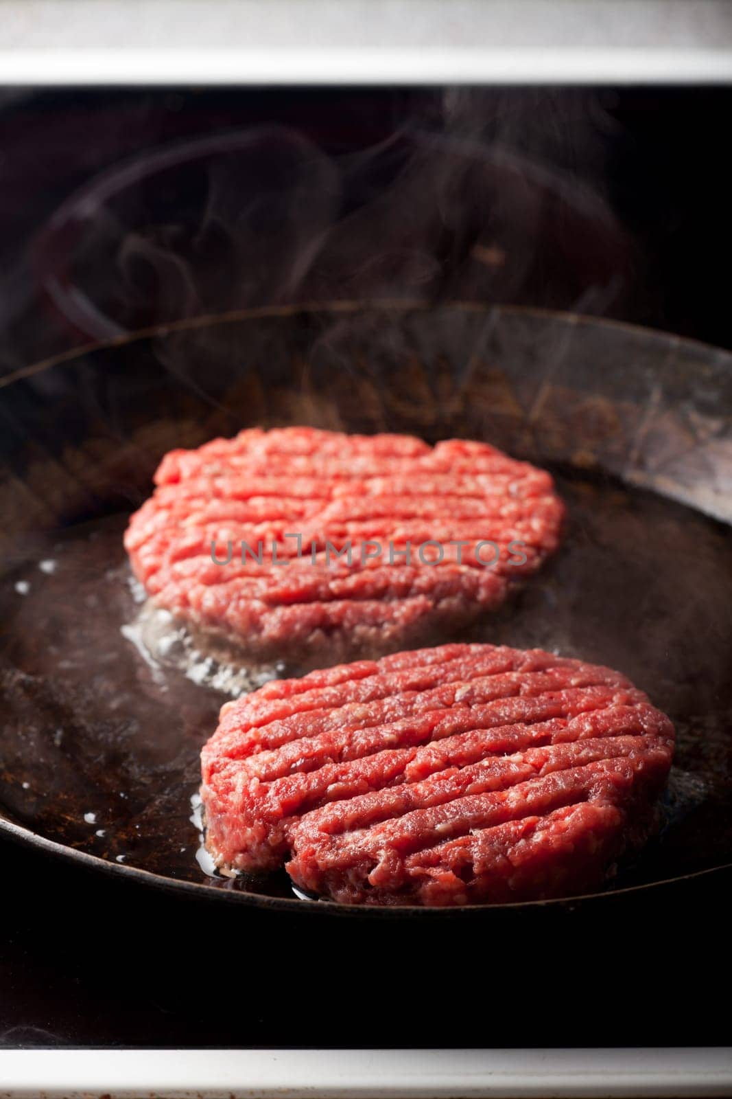 two beef patties in an iron pan