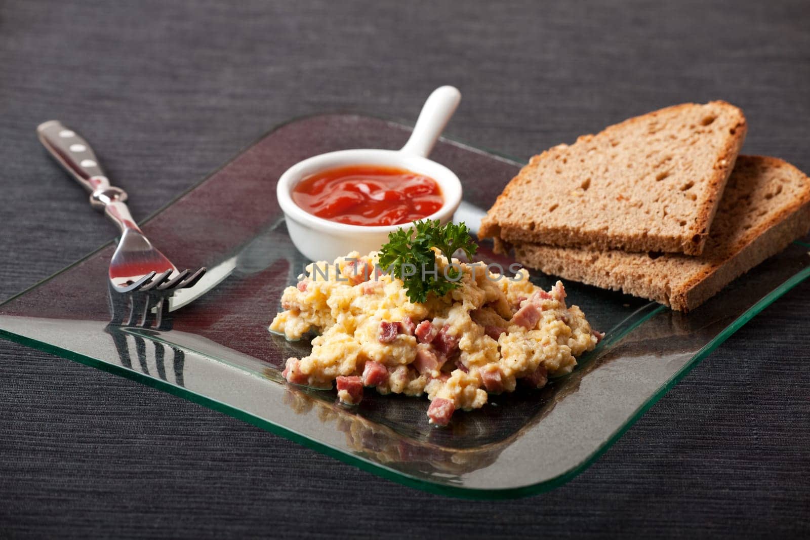 scambled eggs with ham cubes on a glass plate