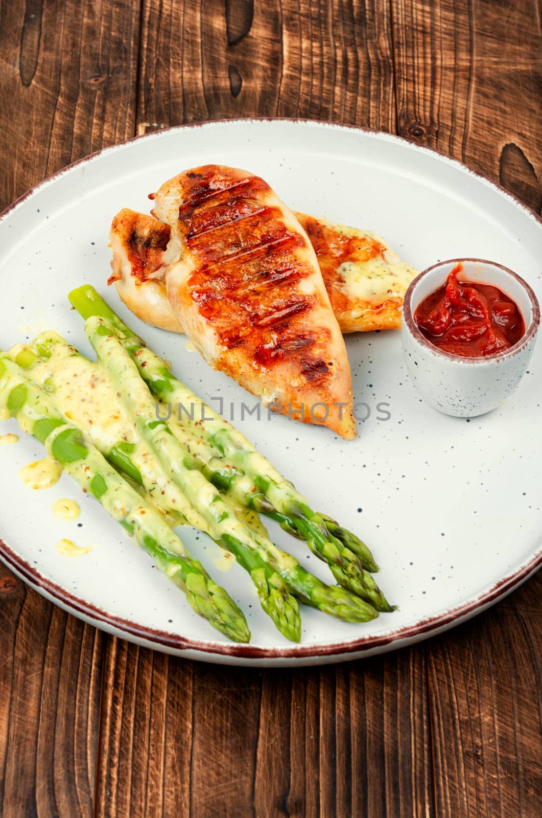 Roasted or grilled chicken breasts with green asparagus. Grilled meat and asparagus. Space for text.