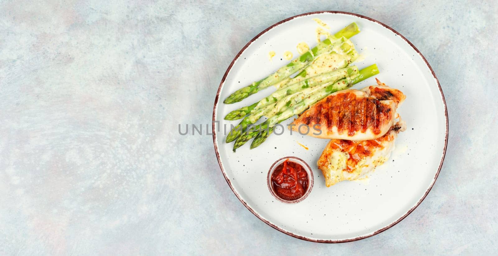 Roasted or grilled chicken breasts with green asparagus. Grilled meat and asparagus. Space for text.