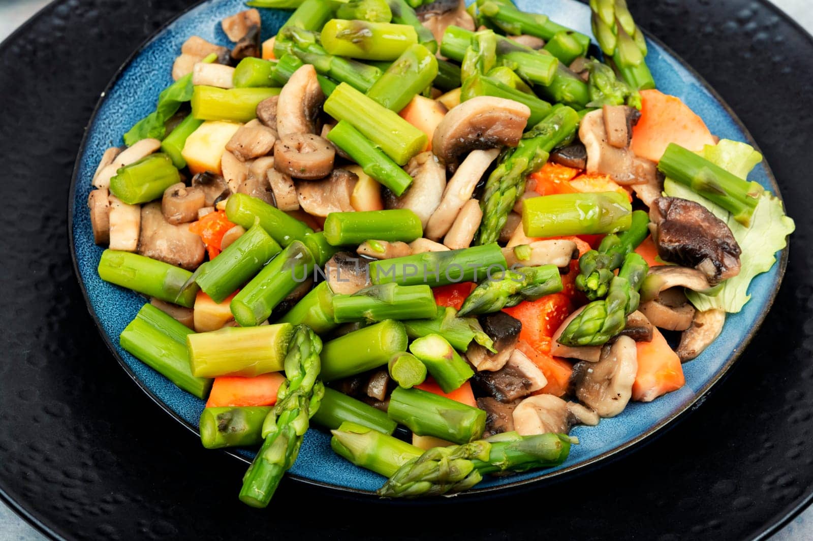 Tasty salad of green asparagus and fried mushrooms on a plate. Vegetable salad.