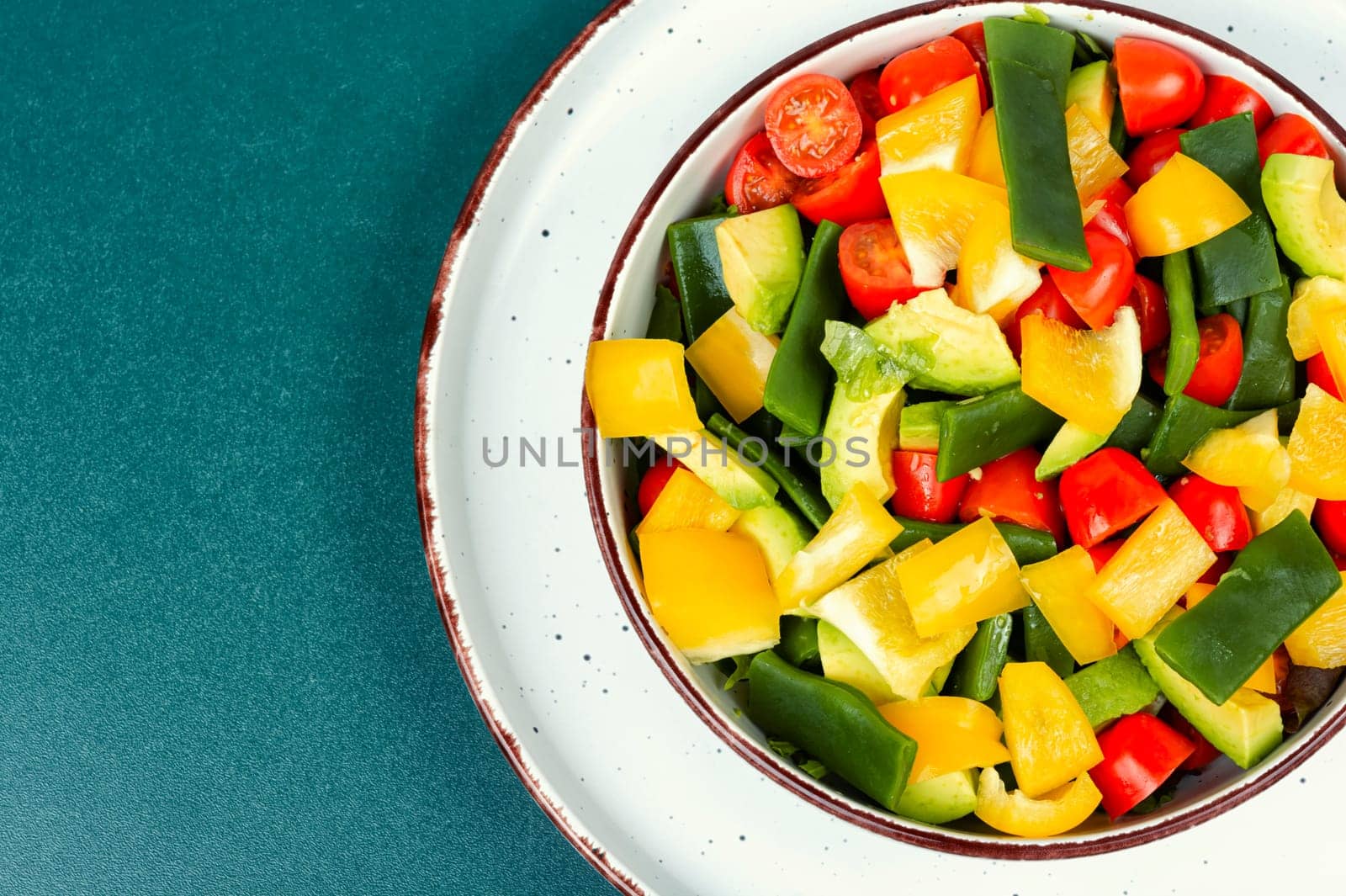 Healthy raw vegetable salad with bell pepper, tomato, avocado and runner beans. Copy space.