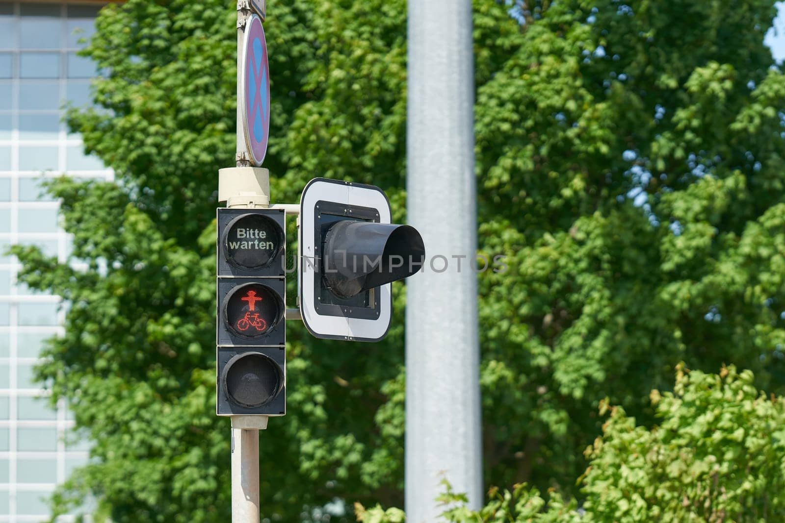 red traffic light in the city center of Magdeburg with the german lettering bitte warten. Translation: please wait