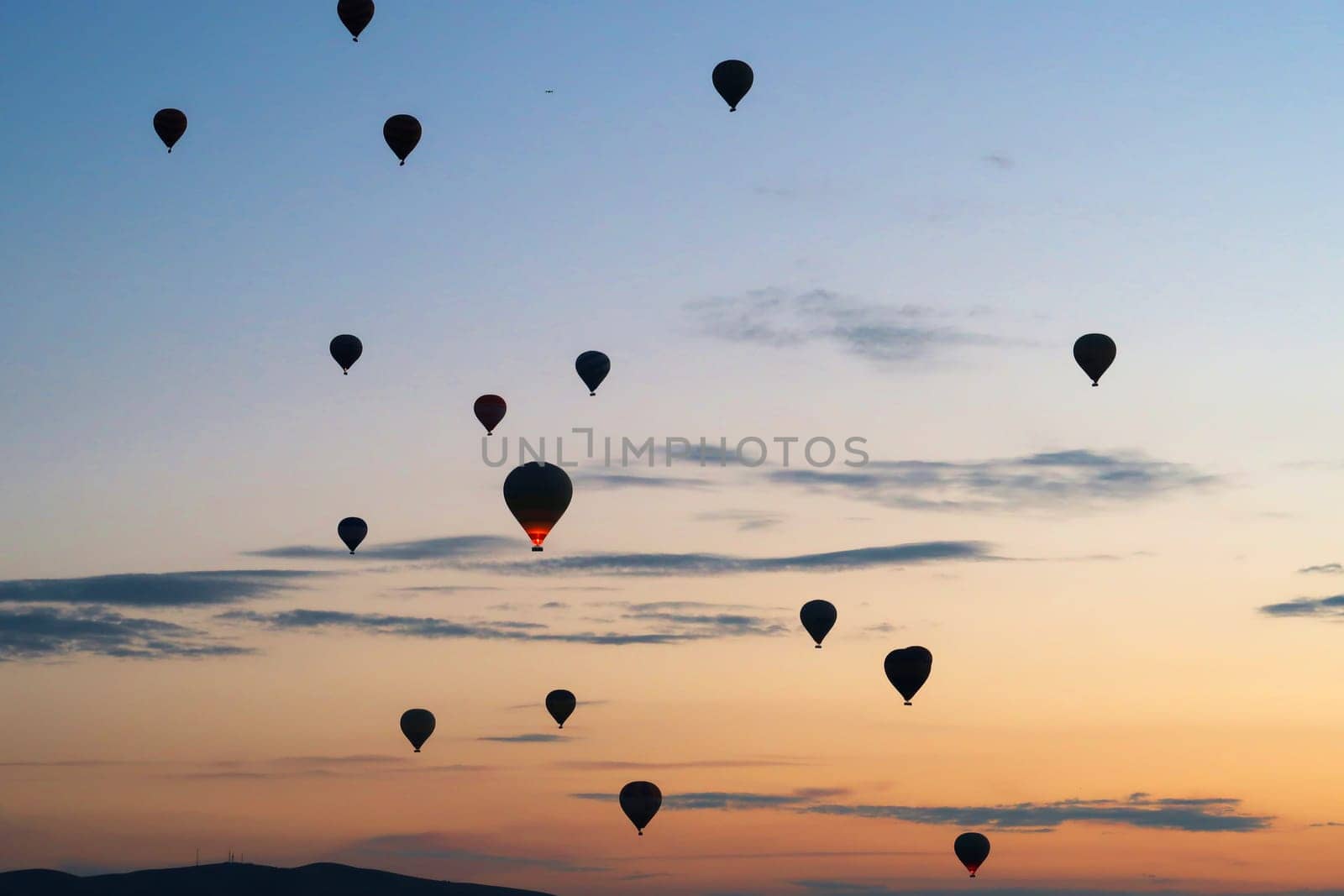 Hot air balloons rising over the landscape of the Red Valley, Rose Valley before sunrise, close to Goreme, Cavusin, Cappadocia, Turkey 2022