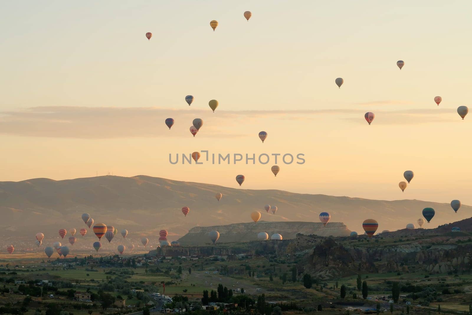 Many colorful hot air balloons over the landscape of the Red Valley, Rose Valley at sunrise, close to Goreme, Cavusin, Cappadocia, Turkey 2022