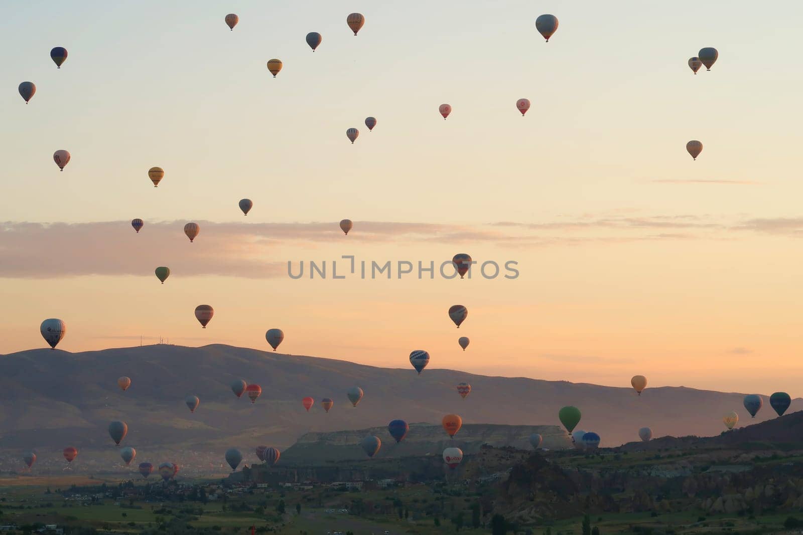 Dozens of colorful hot air balloons over the landscape of the Red Valley, Rose Valley right before sunrise, close to Goreme, Cavusin, Cappadocia, Turkey 2022