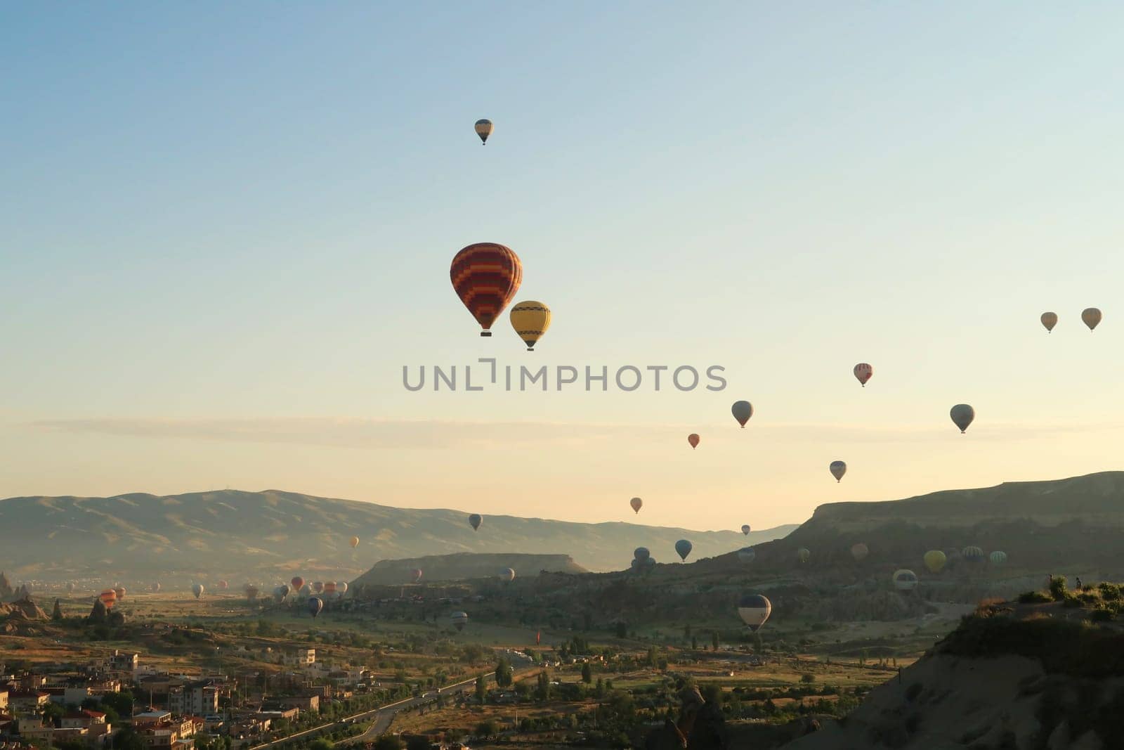 Colorful hot air balloons flying over the landscape of the Red Valley, Rose Valley, close to Goreme, Cavusin, Cappadocia, Turkey 2022