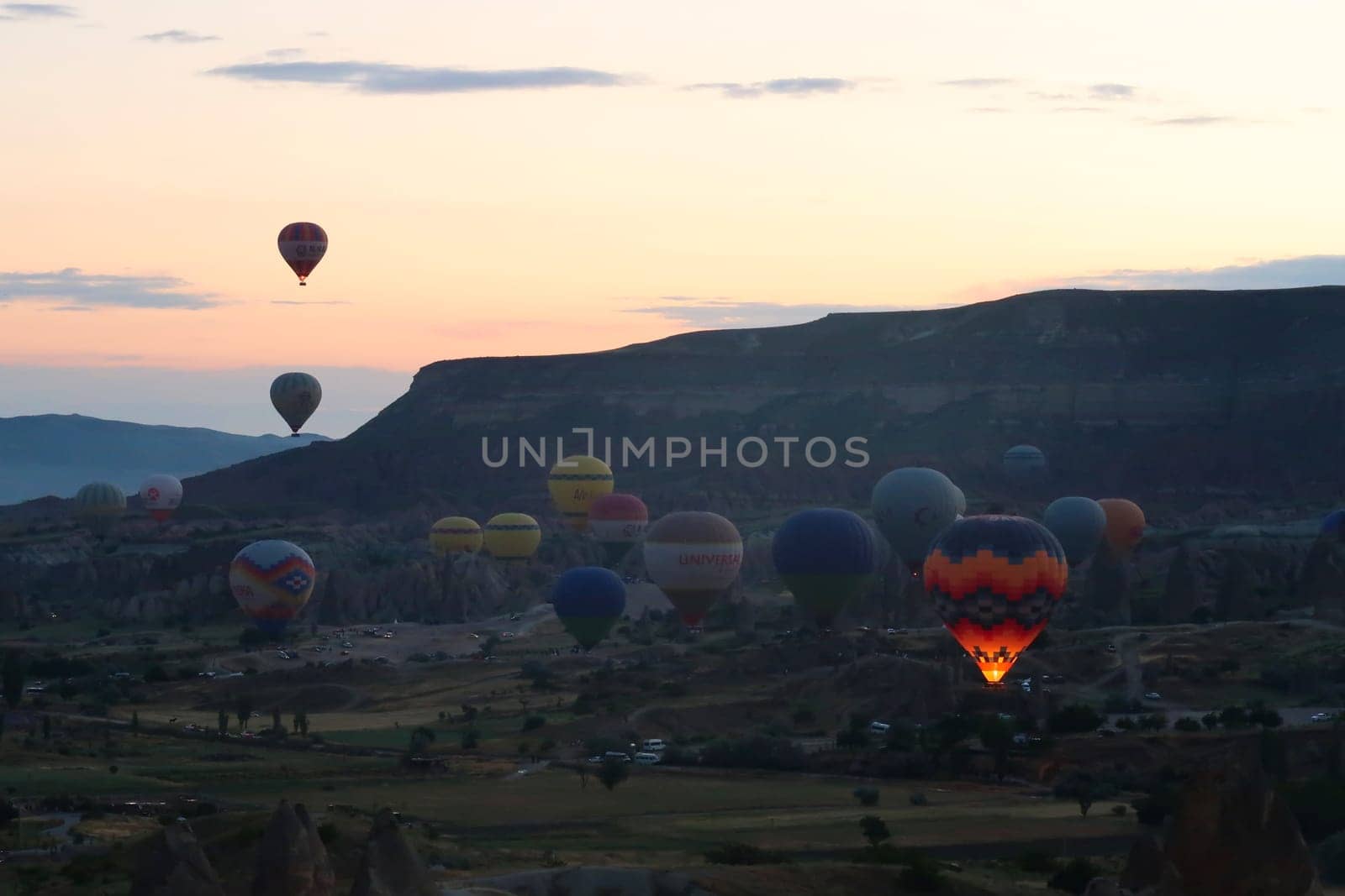 Hot air balloons rising from the balloon take off point next to Rose Valley, Red Valley in the early morning, close to Göreme, Cavusin, Cappadocia, Turkey 2022