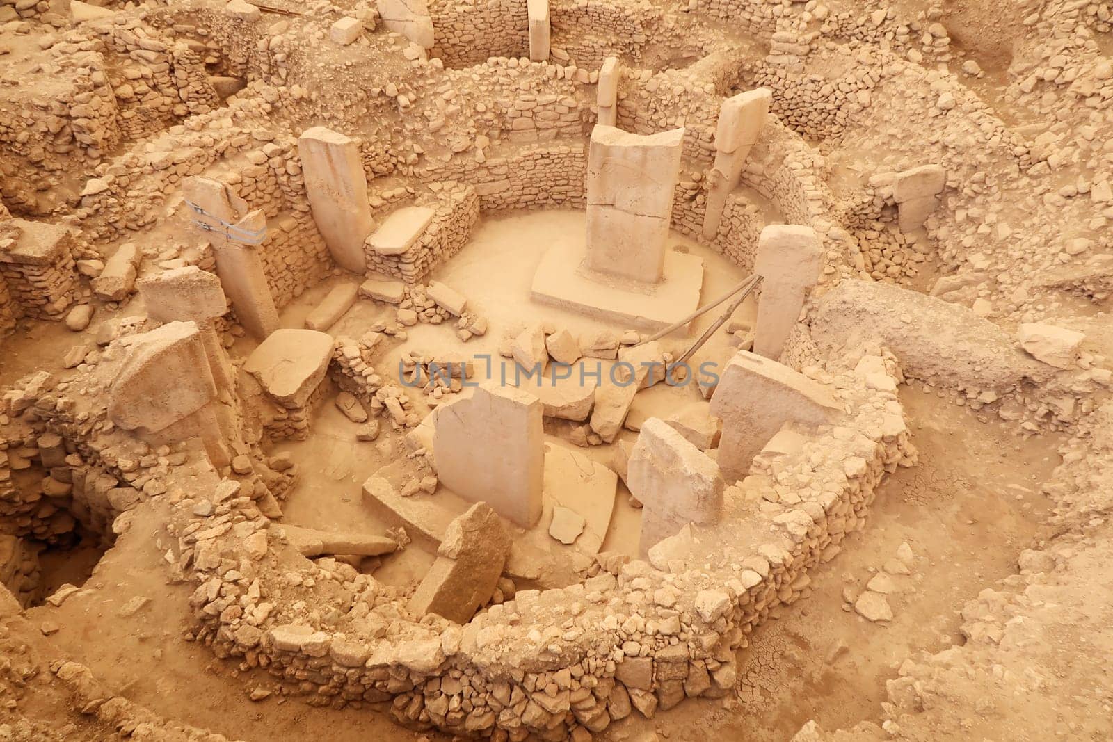 View onto Enclosure C at the neolithic archaeological site of Göbekli Tepe, Potbelly Hill, the central pillar 37 with a fox on it and the pillar 27 with a cat chasing a boar are clearly visible, close to Sanliurfa, Turkey 2022