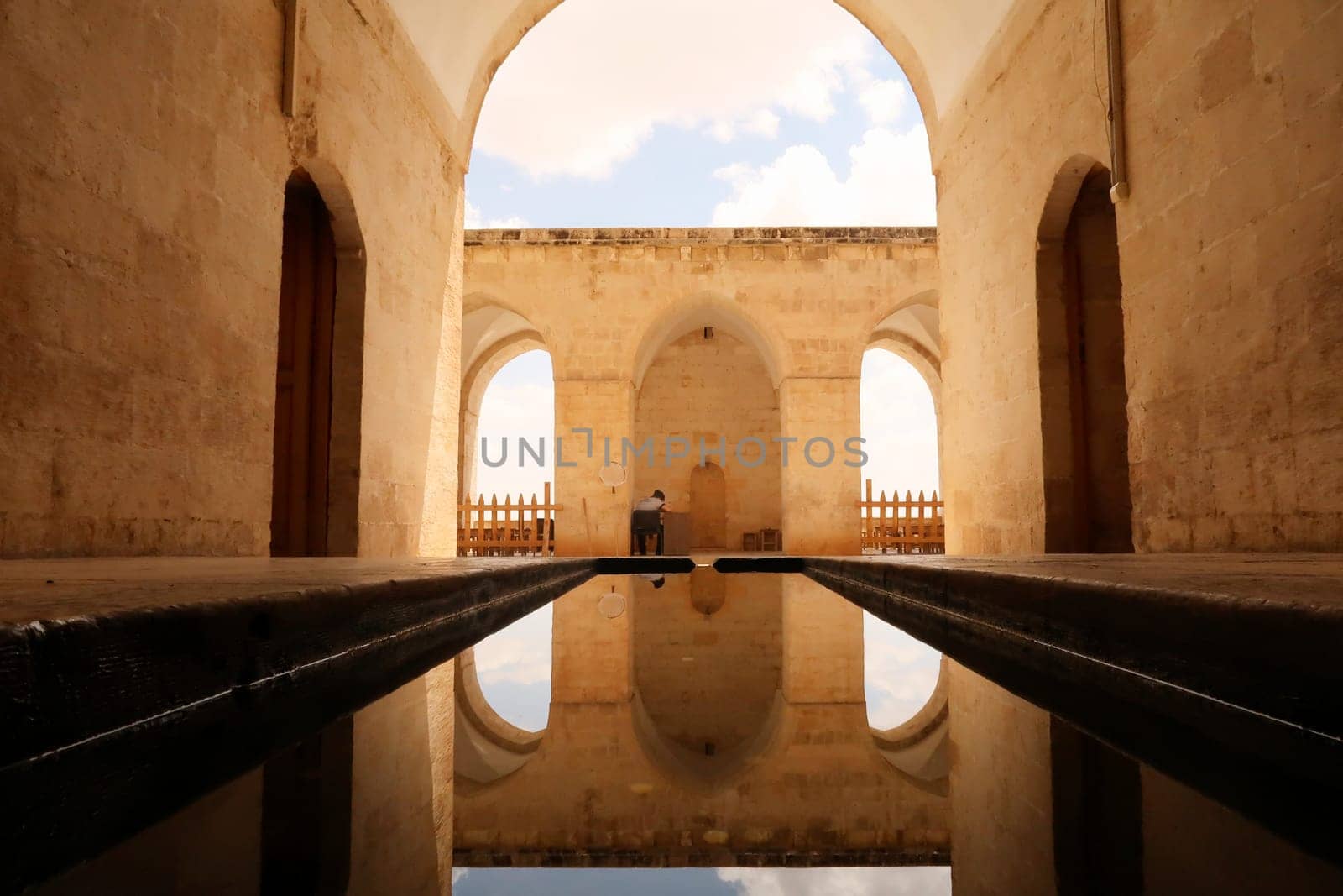Water in a pond, pool reflecting the arches, vaults and doors of the Sultan Isa Medrese, Madrasa, Zinciriye Medrese in the old town of Mardin, Turkey 2022