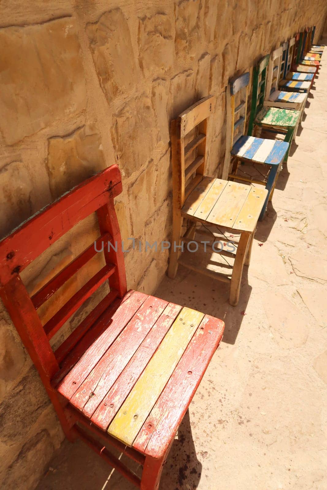 Colorful wooden chairs placed in a row in front of a wall in the old town of Mardin, Turkey 2022