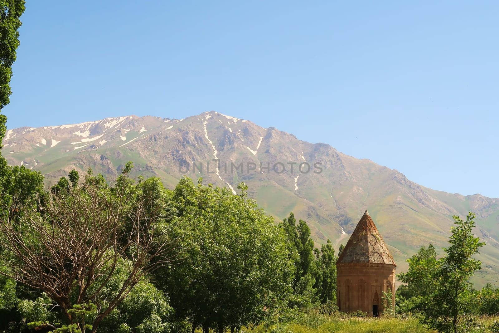 The Halime Hatun tomb, grave, mausoleum, Halime Hatun Kümbeti with the snow covered Mount Artos in the background and a little forest next to it, close to Lake Van, Van Gölü, Gevas, Turkey 2022