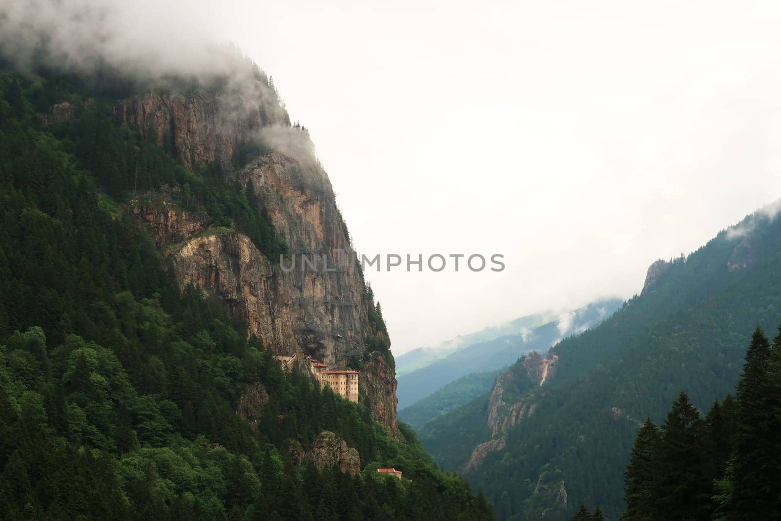 View onto the Sumela, Sümela Monastery, built on a cliff above a dense forest, fog coming up above the cliff, Trabzon, Turkey 2022