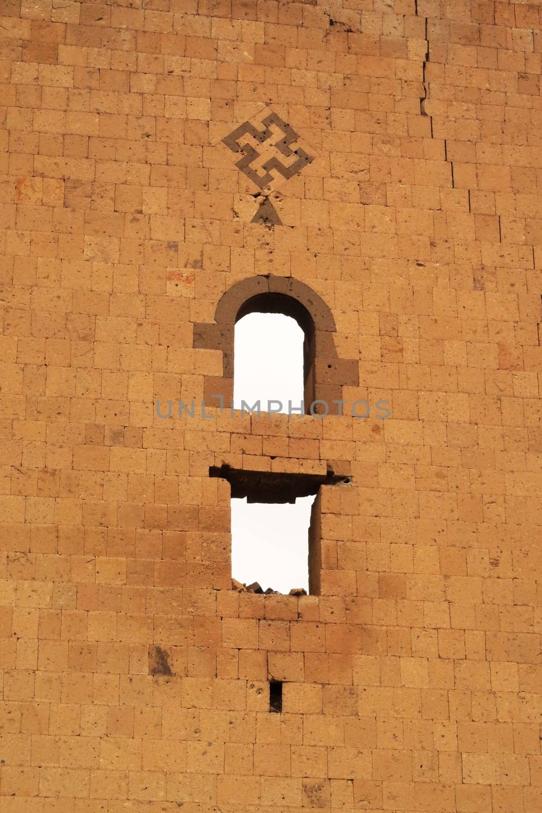Cross symbol and two windows on the back of the tower next to the Lion Gate at the ancient site of Ani, an abandoned ruined armenian city, close to Kars, Turkey 2022