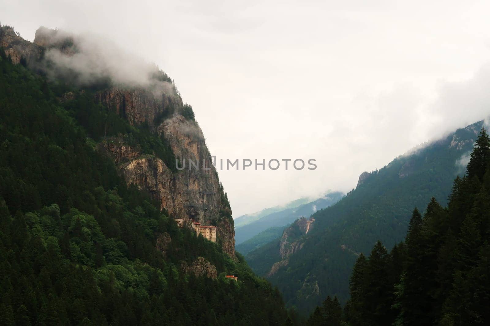 View onto the Sumela, Sümela Monastery and the dense forest that surrounds it, fog coming up above the cliff that it is build on, Trabzon, Turkey 2022