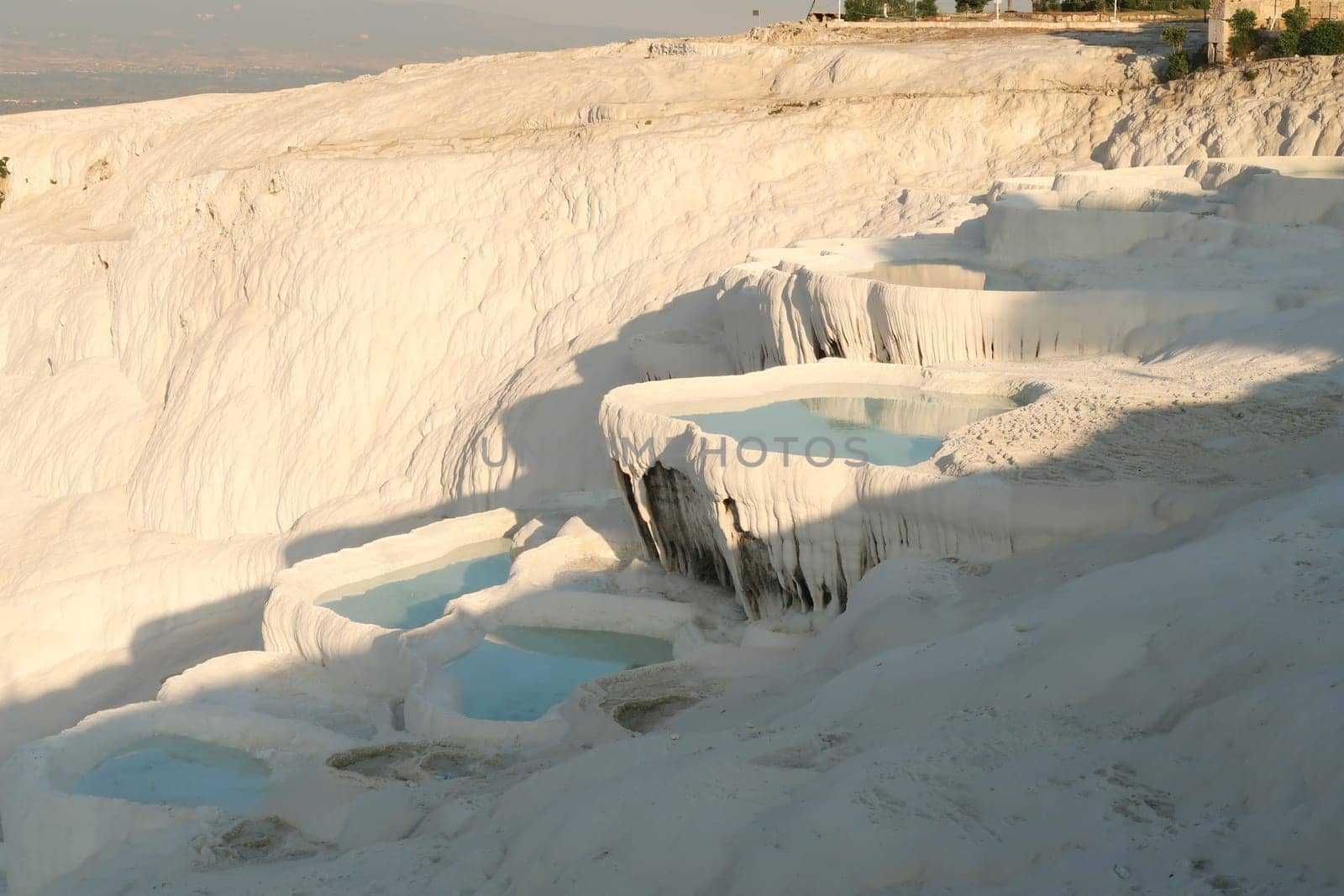 Closer look onto the travertine terraces of Pamukkale, filled with intense blue water, Denizli, Turkey 2022