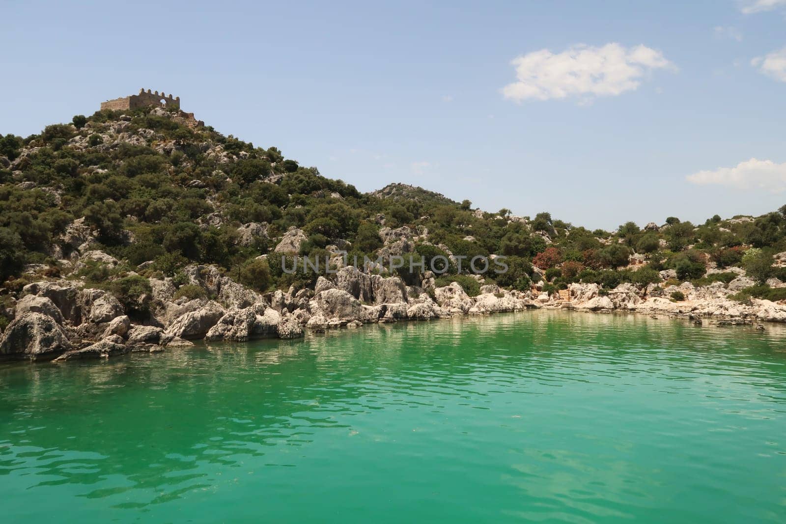 The green water in the Burc Koyu Bay, a roman castle can be seen on a hilltop on the left, close to Demre, Turkey 2022