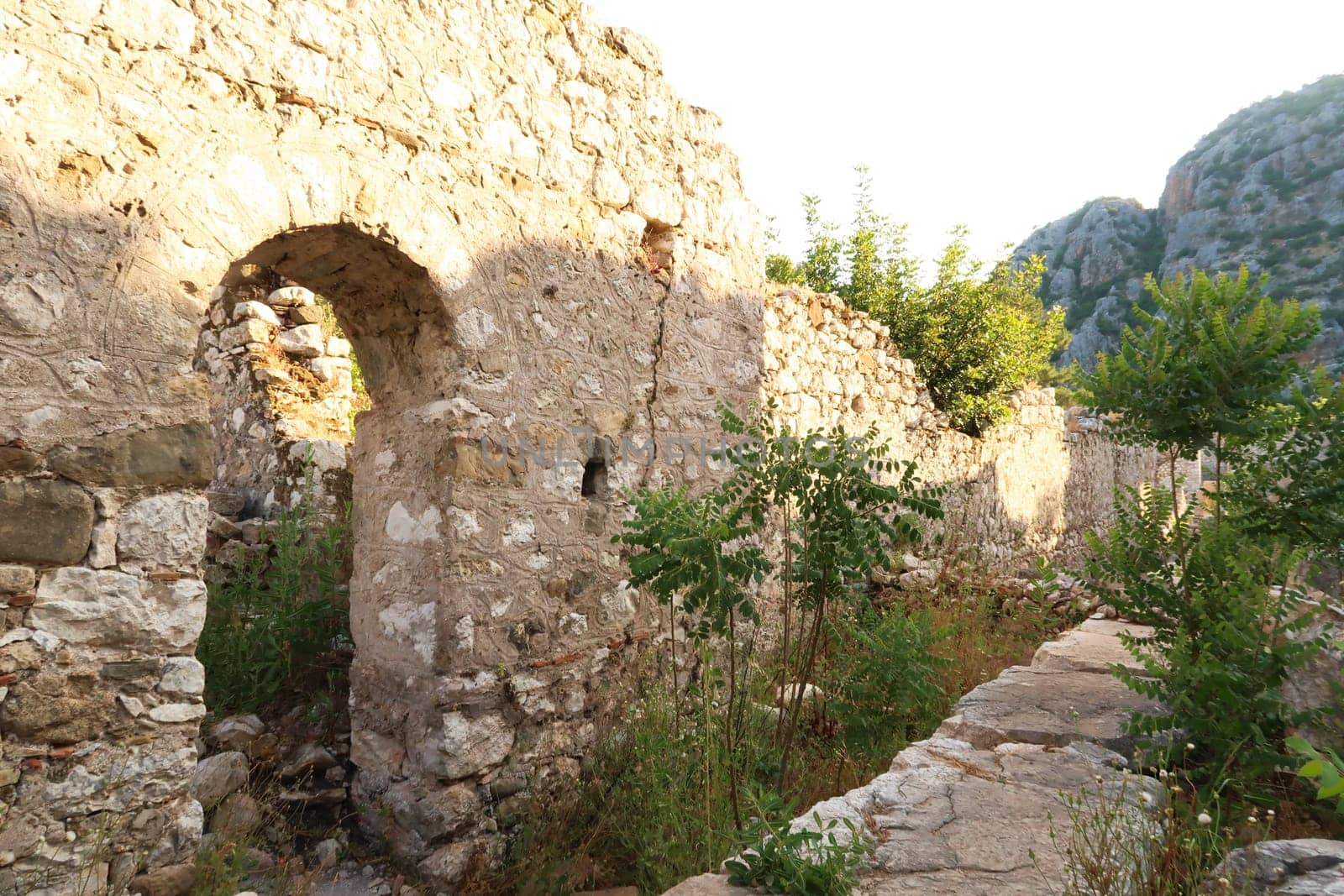 A wall with a door inside the ruins of Church A at the ancient site of Olympos, Olympus, plants, bushes and trees are overgrowing the area, close to Antalya, Turkey 2022
