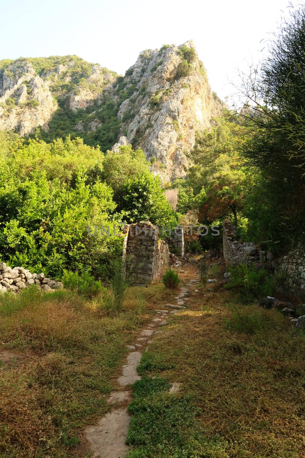 Trail leading through the ruins across the river at the ancient site of Olympos, Olympus with a mountain in the background, close to Antalya, Turkey 2022