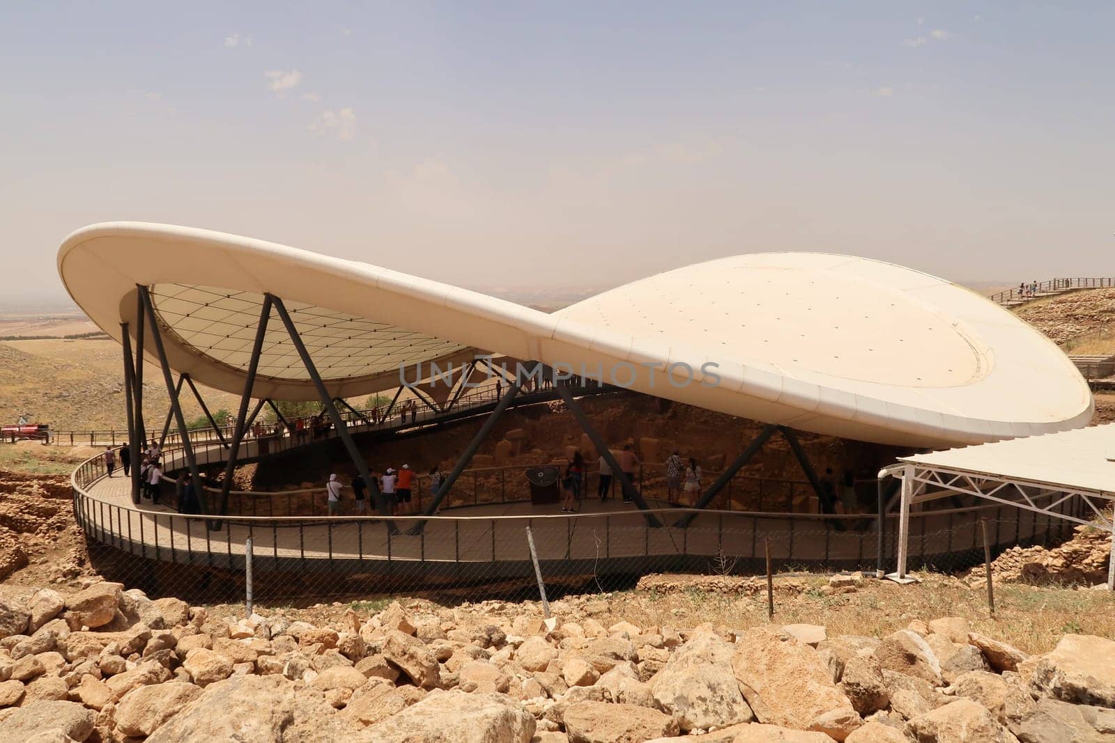 View onto the protective roof and the wooden walkway build around the neolithic archaeological site of Göbekli Tepe, Sanliurfa, Turkey, 12th of June 2022