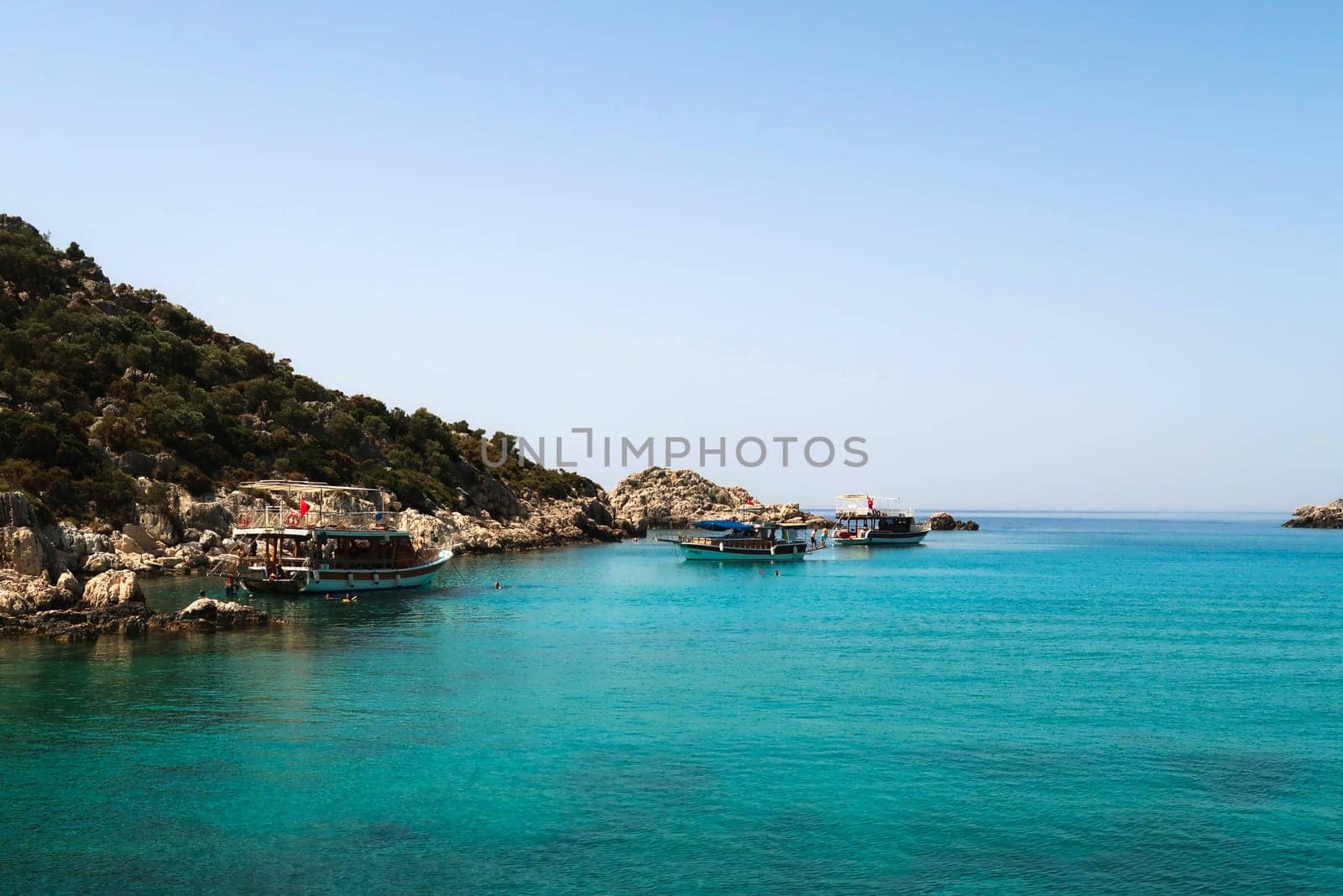 Several boats anchoring on the Kekova boat tour so that the tourists can go swimming and snorkeling, Demre, Turkey, 27th of May 2022