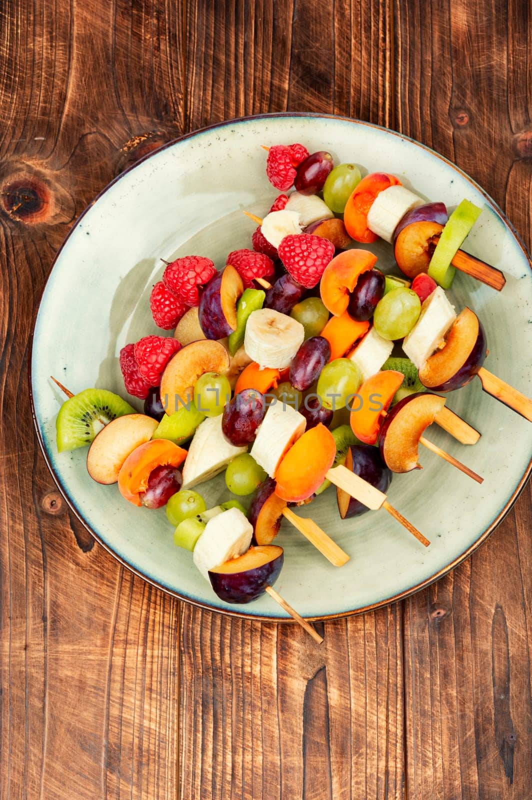 Colorful fruit skewers made from fresh fruits on wooden skewers.