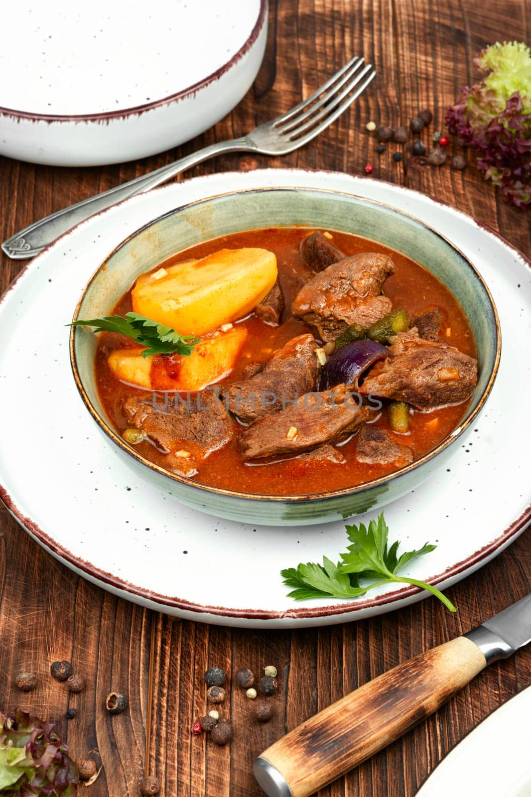 Stewed deer goulash in sauce, venison goulash. Deer ragout on rustic wooden surface.