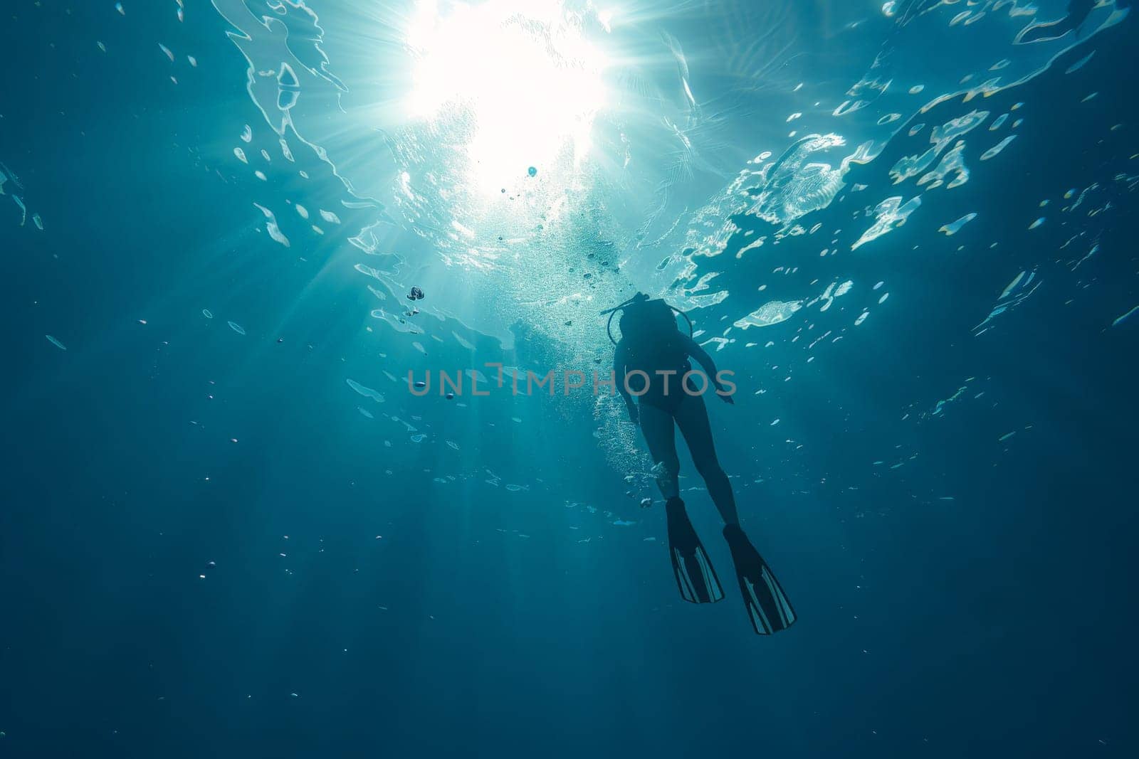 A lone diver ascends towards the sunburst above, surrounded by the serene blue of the oceans embrace.