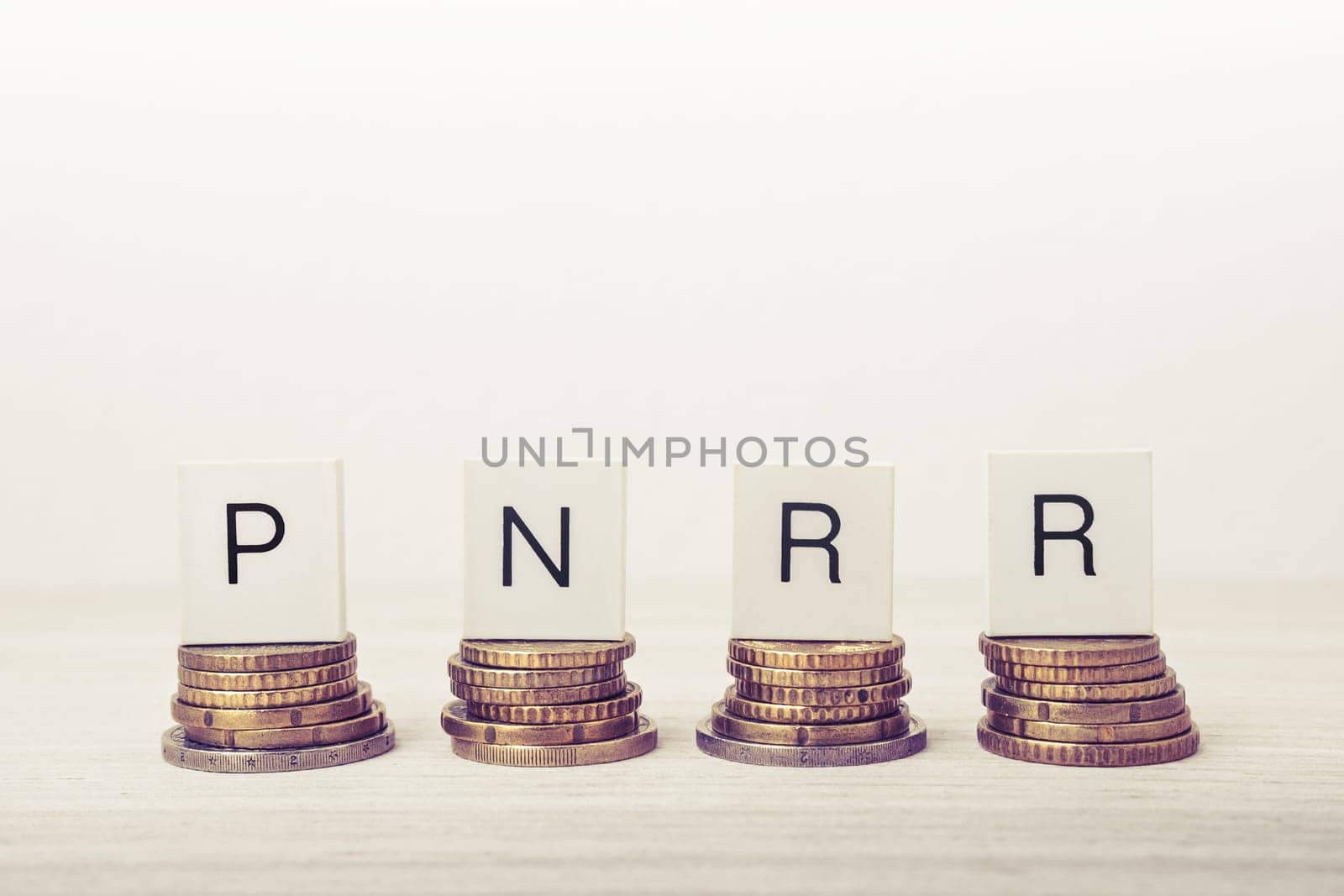 Stacks of coins with PNRR letters on white background. UE economy concept.