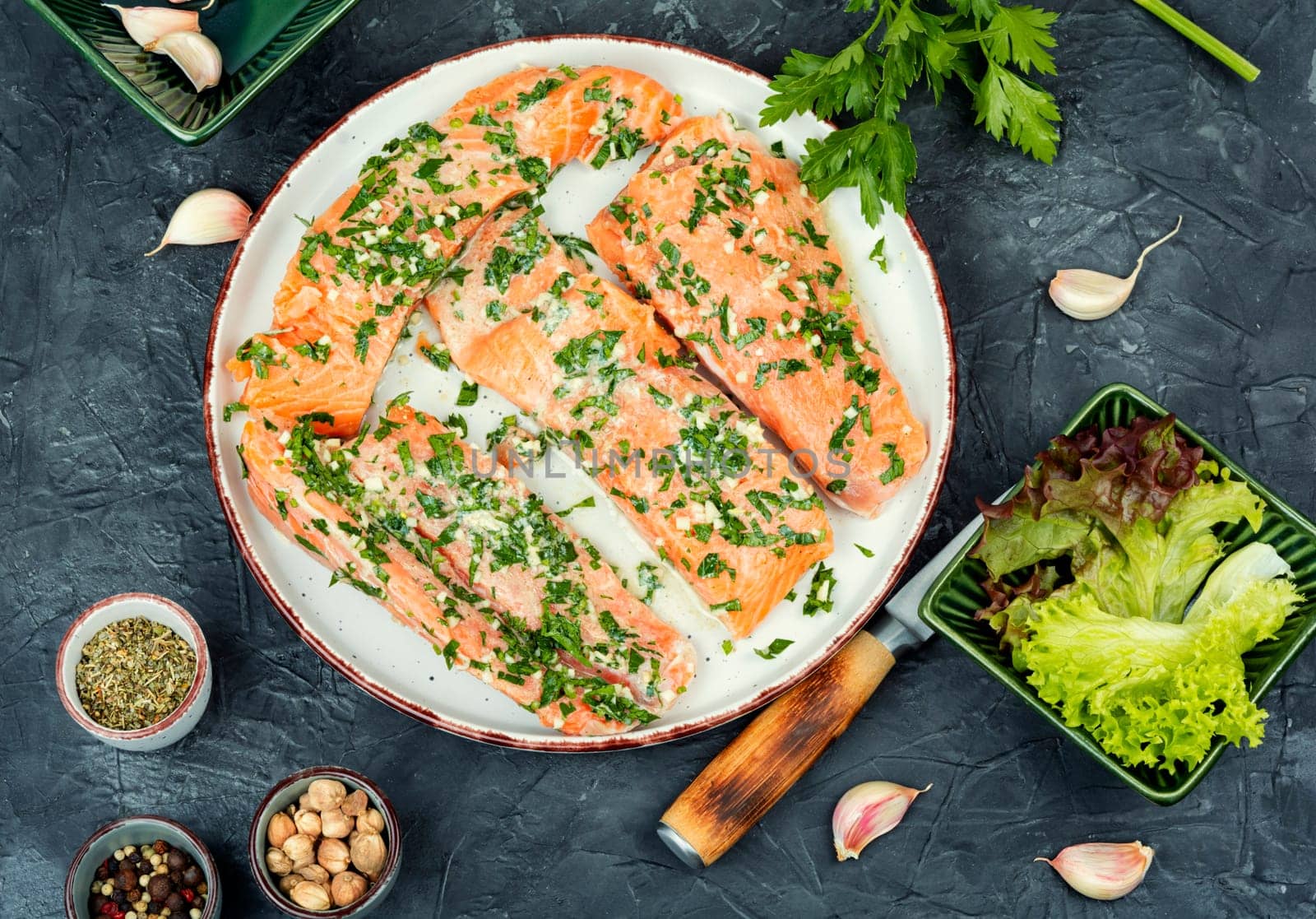 Fresh raw salmon fillet fish in garlic herbs marinade ready for baking. Close up.