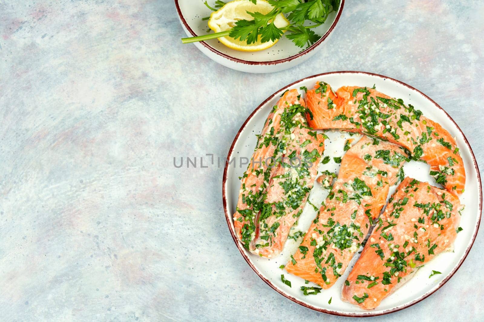 Fresh raw salmon fillet fish in garlic herbs marinade ready for baking. Close up.