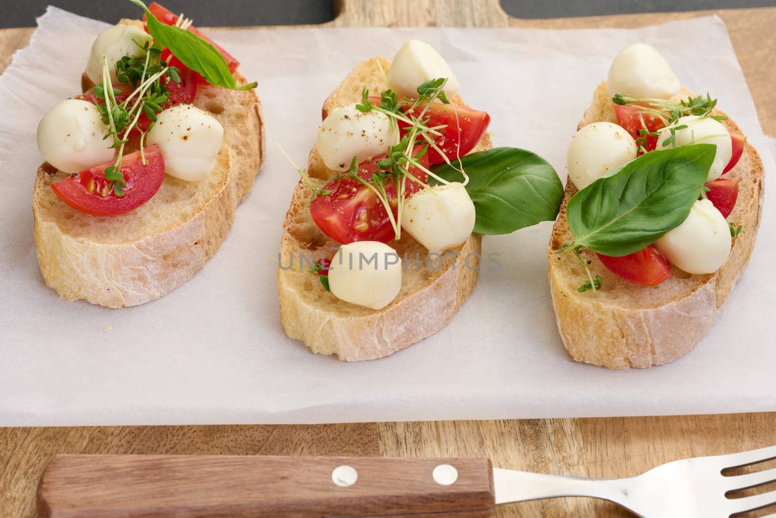 Round mozzarella, cherry tomatoes and microgreens on a piece of white bread, a healthy sandwich
